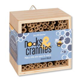 Image of the Nooks & Crannies Insect Block in the shape of a wooden square box width bamboo sticks placed horizontally creating cavities for the insects. The insect block is partially wrapped with packaging that reads "Nooks & Crannies Insect Block"