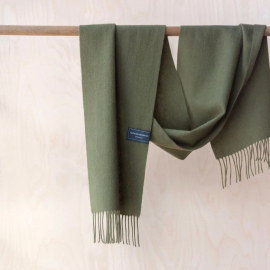 Lambswool Scarf, olive hanging from a wooden pole