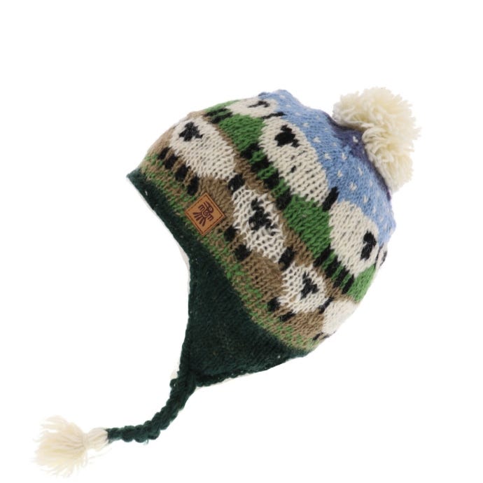 Wool chullo featuring a blue sky and sheep placed on lush grass. Cream bobble.