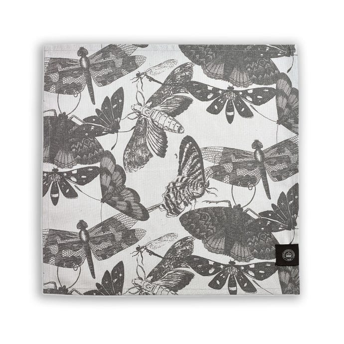 One napkin from the set of four napkins inspired by the stunning and intricate artwork found in the extensive Royal Botanic Gardens, Kew. Light grey napkins with darker grey artwork of insects including butterflies and dragonflies. Kew logo featured in bo