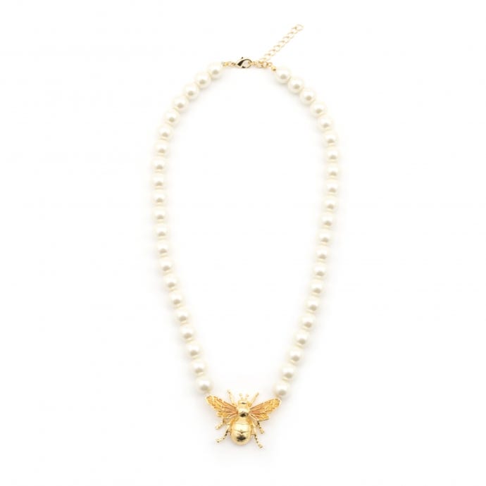 The necklace features an oversized bee with rich 18ct gold plate, hues of yellow enamel fill the intricate wings. Set on a stand of simulated cream pearls