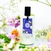 White bottle of the Bluebell and Jasmine Eau de Toilette with label and black lid. White background with flowers surrounding.