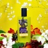 Green Narcissus Lime bottle with black cap, green background surrounded by flowers and sliced lime.