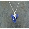 Image of the necklace featuring an iris-shaped pendant in blue-violet colour. The necklace chain is in metal silver as the casting of the pendant and it lays on a marbled surface