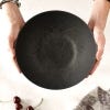 Image of hands holding the bowl with cherries on the table below.