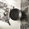 Cereal bowl on white table with tea towels from the range and a spoon surrounding. 