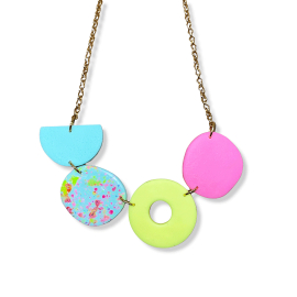 Colourful statement necklace on a gold chain made from handmade polymer clay. On the gold chain, we can see a blue half circle, a blue full circle featuring pink and green speckles, a green ring circle and a pink circle.